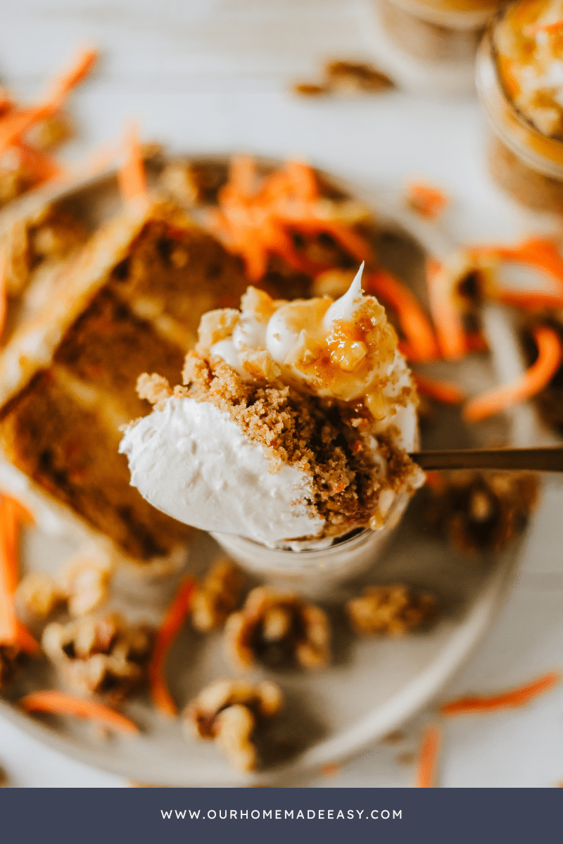 cheesecake layers on spoon carrot cake in background