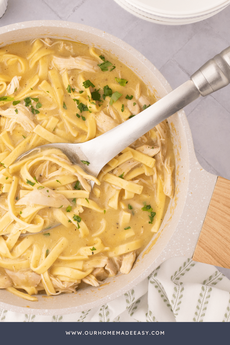 chicken and noodles noodles in cast iron pot with serving spoon